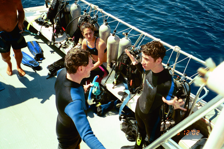 Jared motions to Donald about his first dive while diving-buddy Adlin looks on