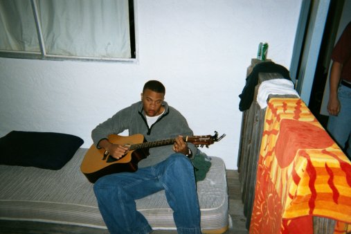 Drake lays on a mattress out on the deck and strums a guitar. (Photo Courtesy of Bryon Farris)